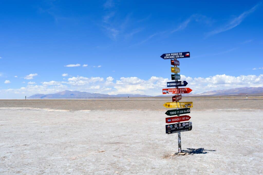 A pole on salt plains with signs pointing in several different directions.