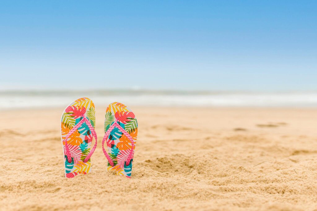 Colourful Flip Flops Slipper in the Beach Sand representing the various landscapes in Nigeria with a coastline of 1372.77 km.