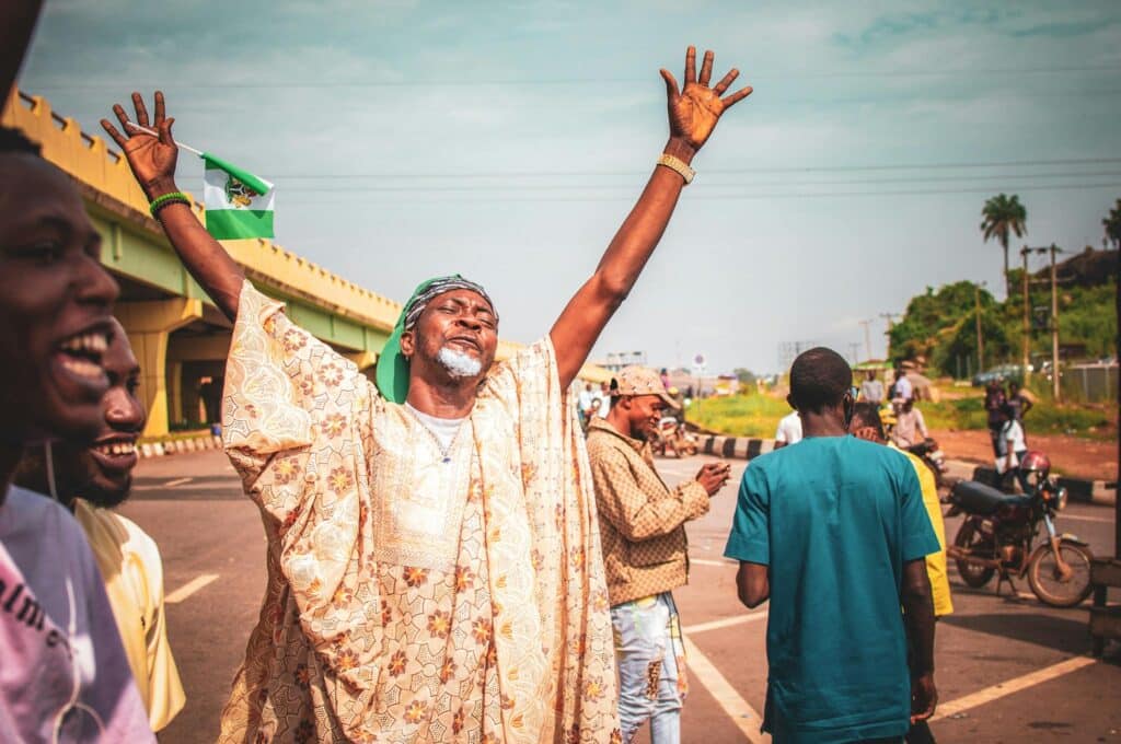 Nigeria beckons as your next adventure, captured in the joyous expression of a man with raised hands. 