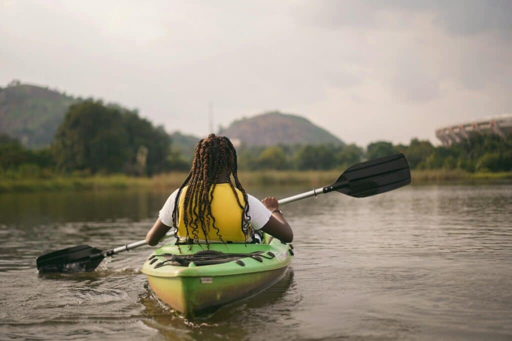 A serene scene of a girl on a paddle boat, surrounded by the breathtaking natural wonders of Nigeria. 