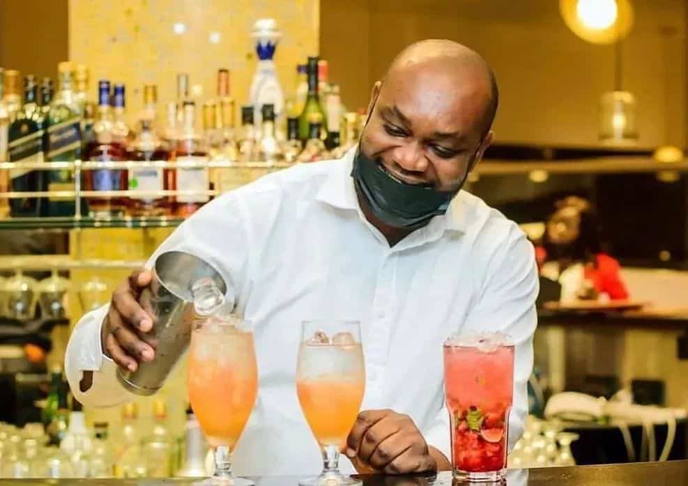 Cheerful bar staff pouring a drink at a bustling pub in Lagos, showcasing the city's vibrant nightlife