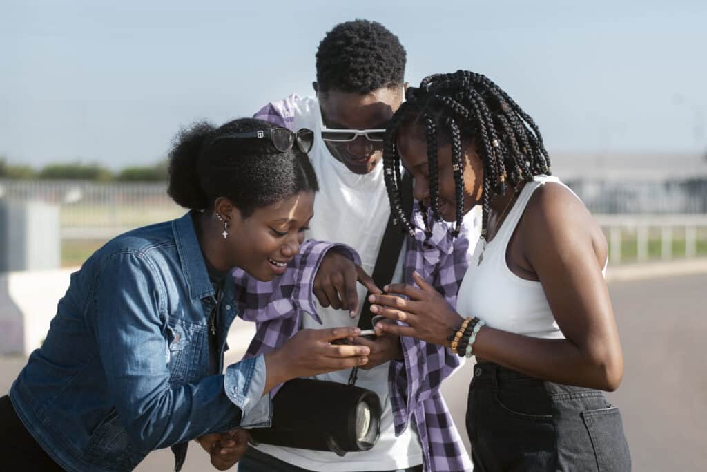 A group of Nigerian youths is looking into a phone. Nigerian youths are known to speak pidgin English, as it is the most popular among them. When you ask how many languages are in Nigeria, pidgin might be the first to be mentioned.