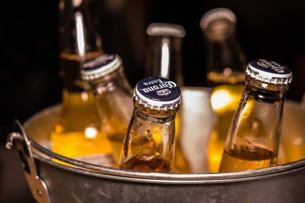 A refreshing display of Corona beers chilling in an ice bucket, ready to be enjoyed, evoking the anticipation of a calm and relaxing moment shared with friends or family.