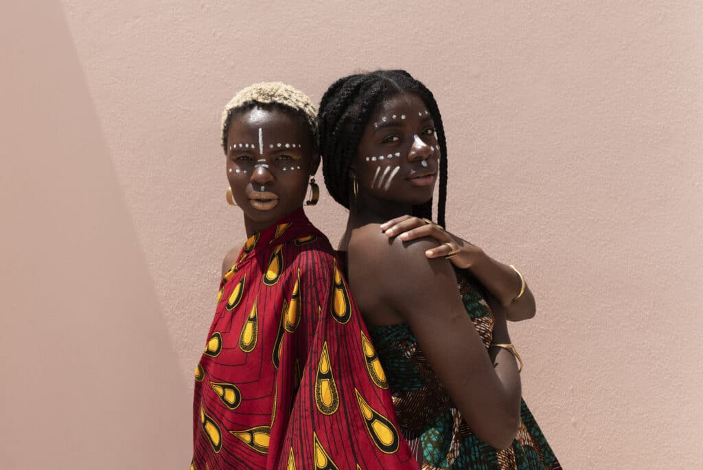 Two Bura women stand side by side, wearing traditional Bura attire. Their beautiful jewellery and demeanour show the richness of the culture.