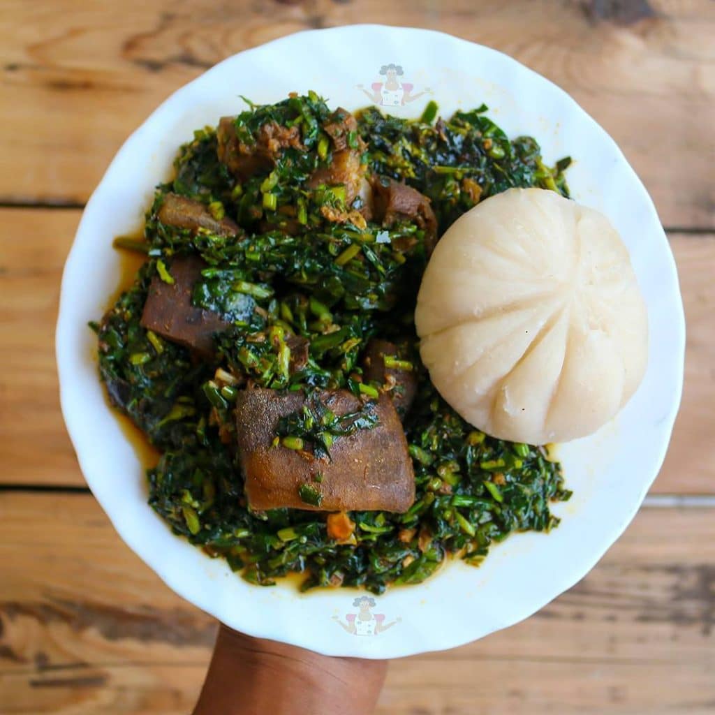 An appetizing bowl of Edikaikong Soup, a traditional Nigerian soup featuring a vibrant mix of green vegetables, assorted meats, and savory spices simmered to perfection.