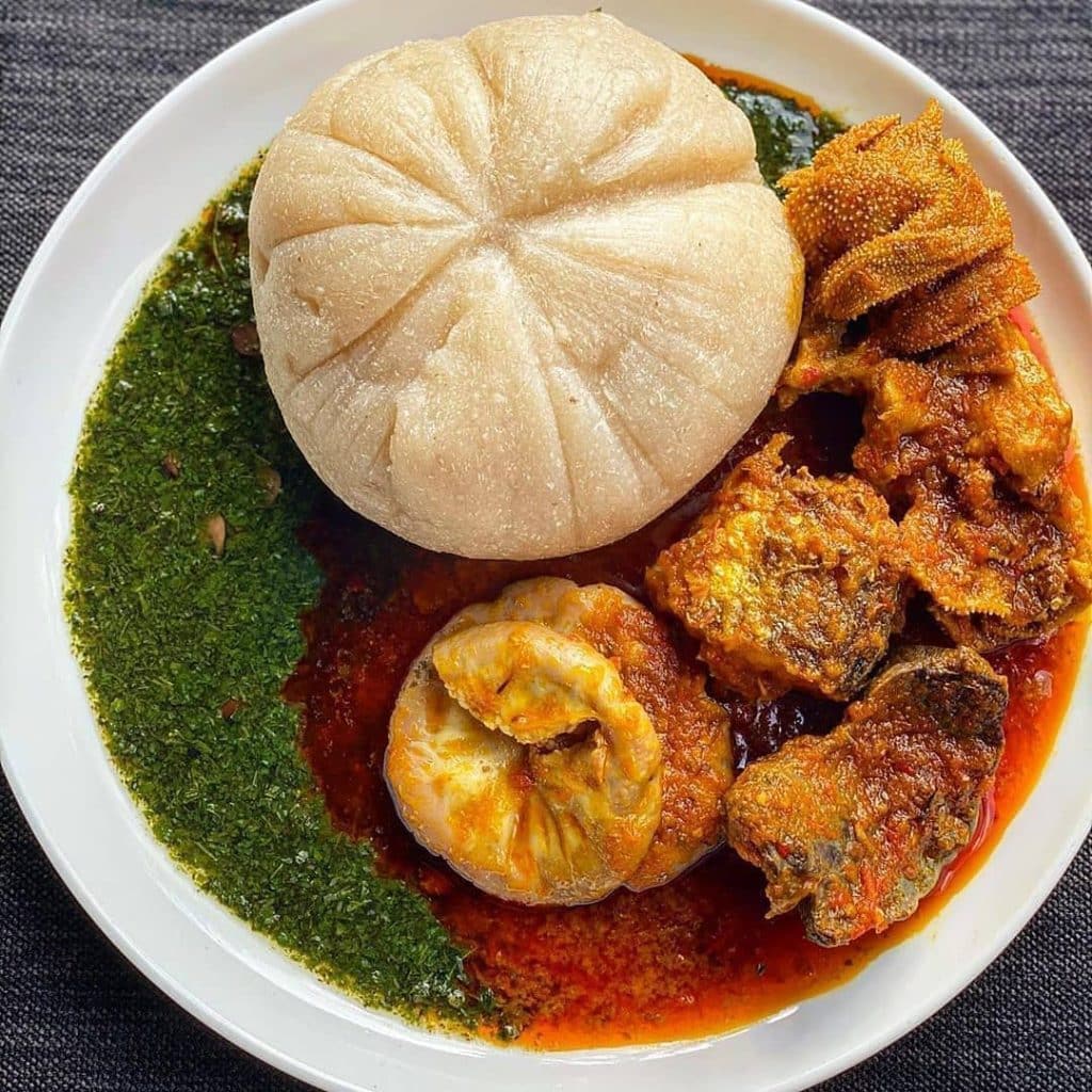 An appetizing bowl of Ewedu Soup, a traditional Nigerian soup made from jute leaves, served with assorted meats and accompanied by fufu. 