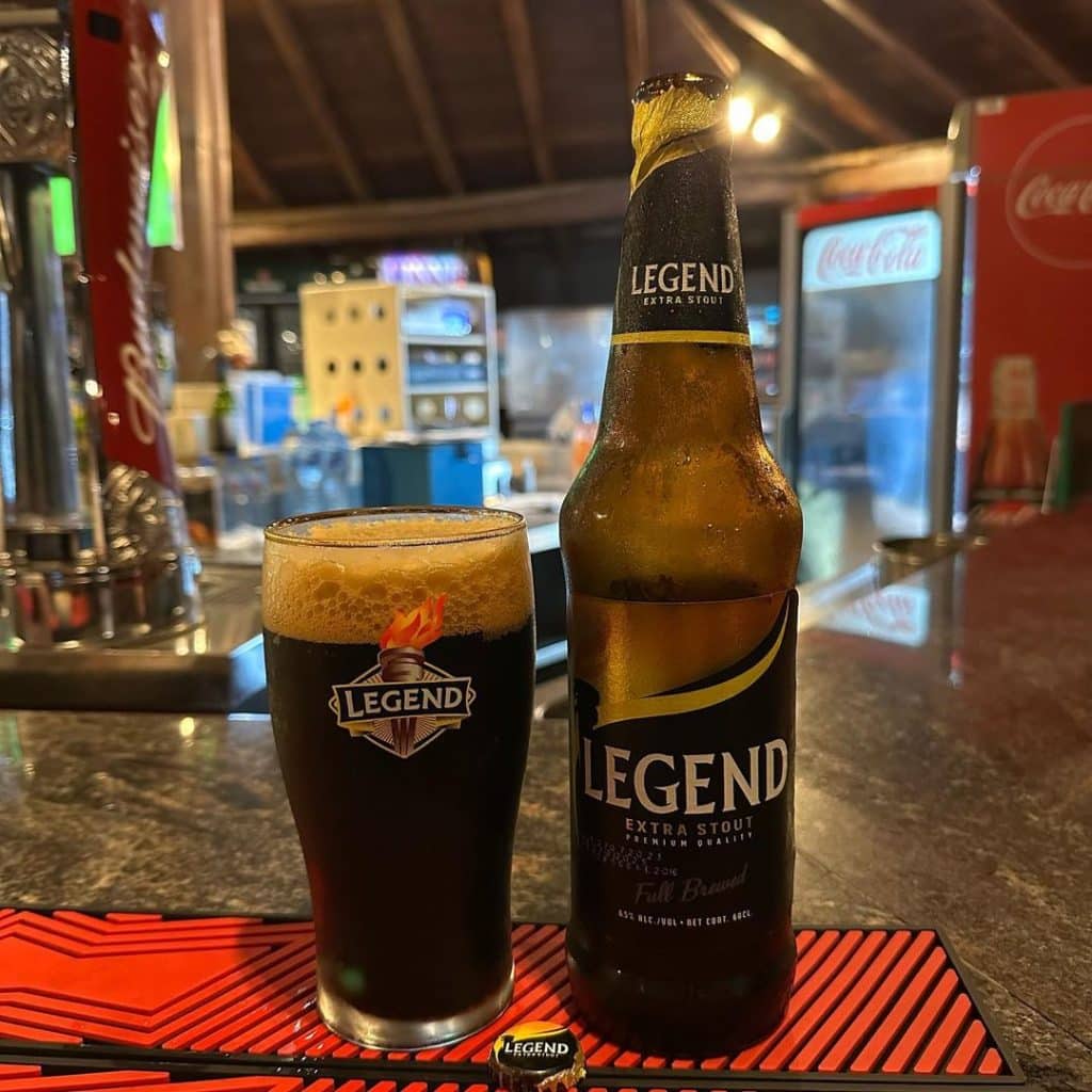 A bottle and glass of Legend beer on a table. Legend, considered one of the best Nigerian beers, is known for its rich, malty flavor.