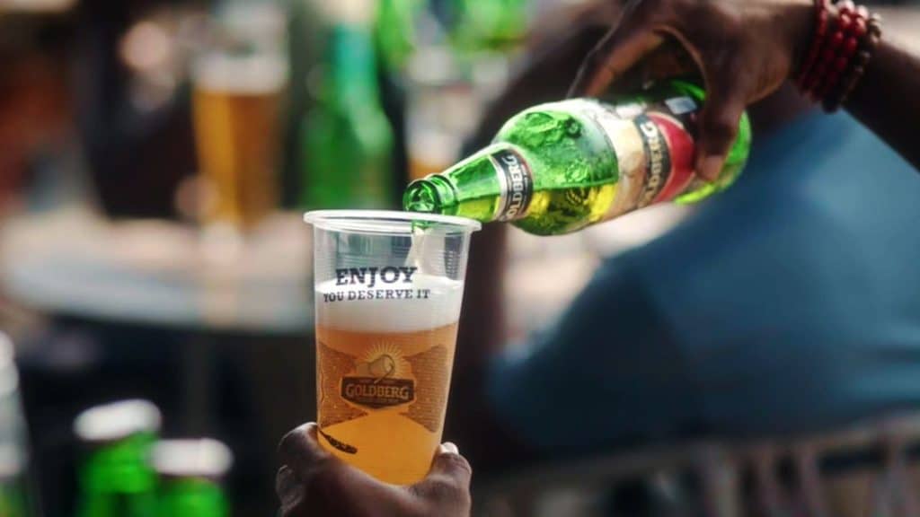 An image of a person pouring Goldberg, one of Nigeria's best beers, from the bottle into a cup.